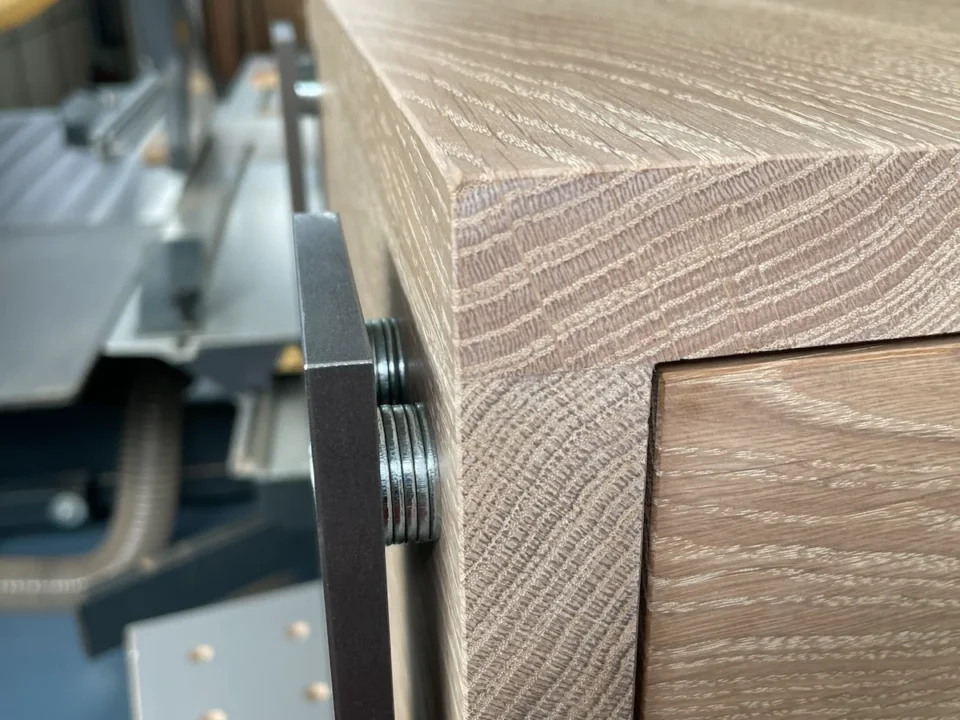 Nahaufnahme von einem Holznachttisch mit Stahlbeinen, der Fokus auf der Verankerung.