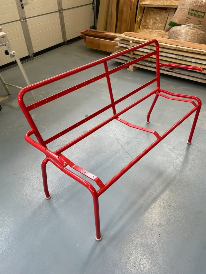 Roter Metallrahmen einer Gartenbank in einer Werkstatt.