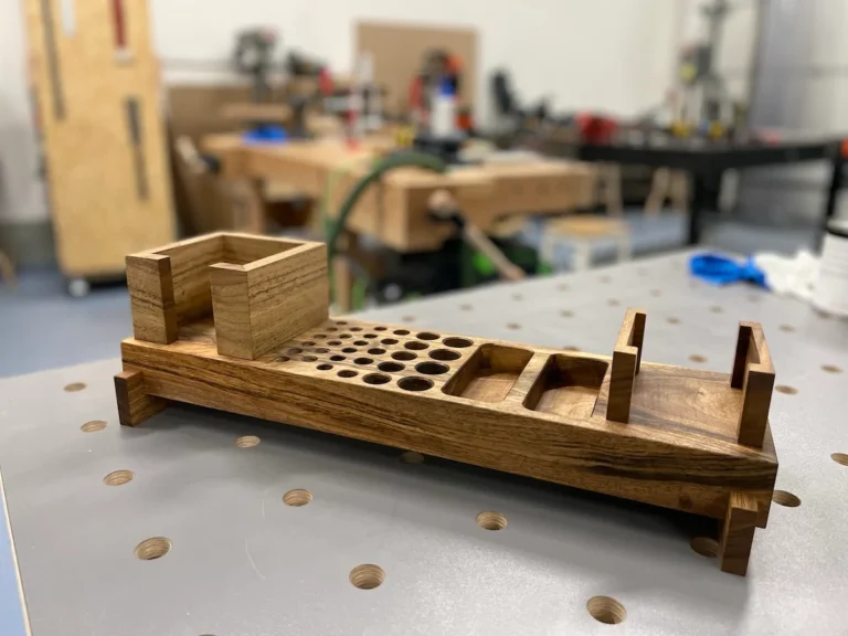 Ein Tischorganizer aus Holz platziert auf einem Metallarbeitstisch in einer Werkstatt.